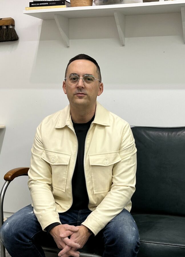 Artist Andrew Casto seated indoors for portrait headshot.