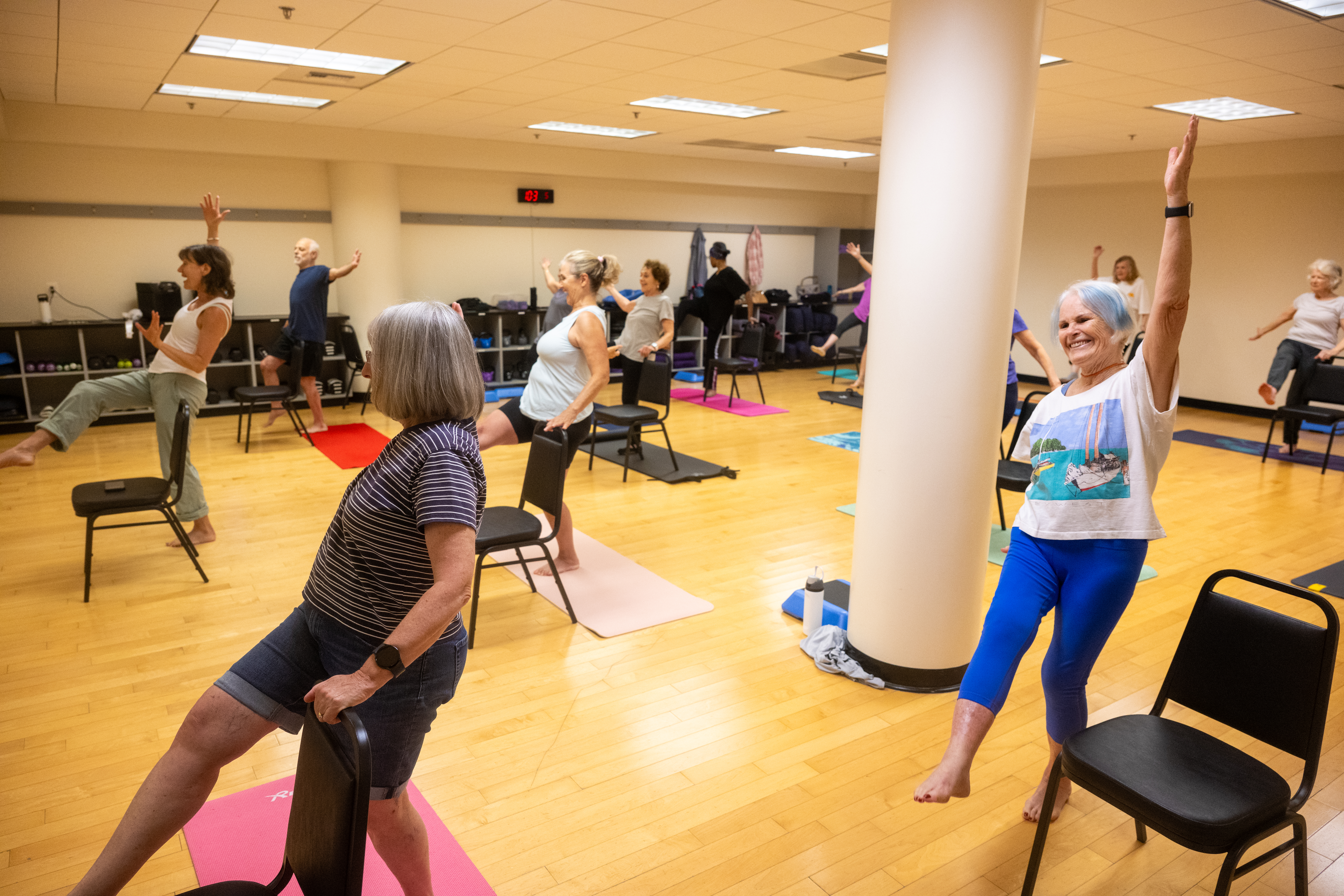 Group of participants balancing on one leg with arms raised in a yoga studio.