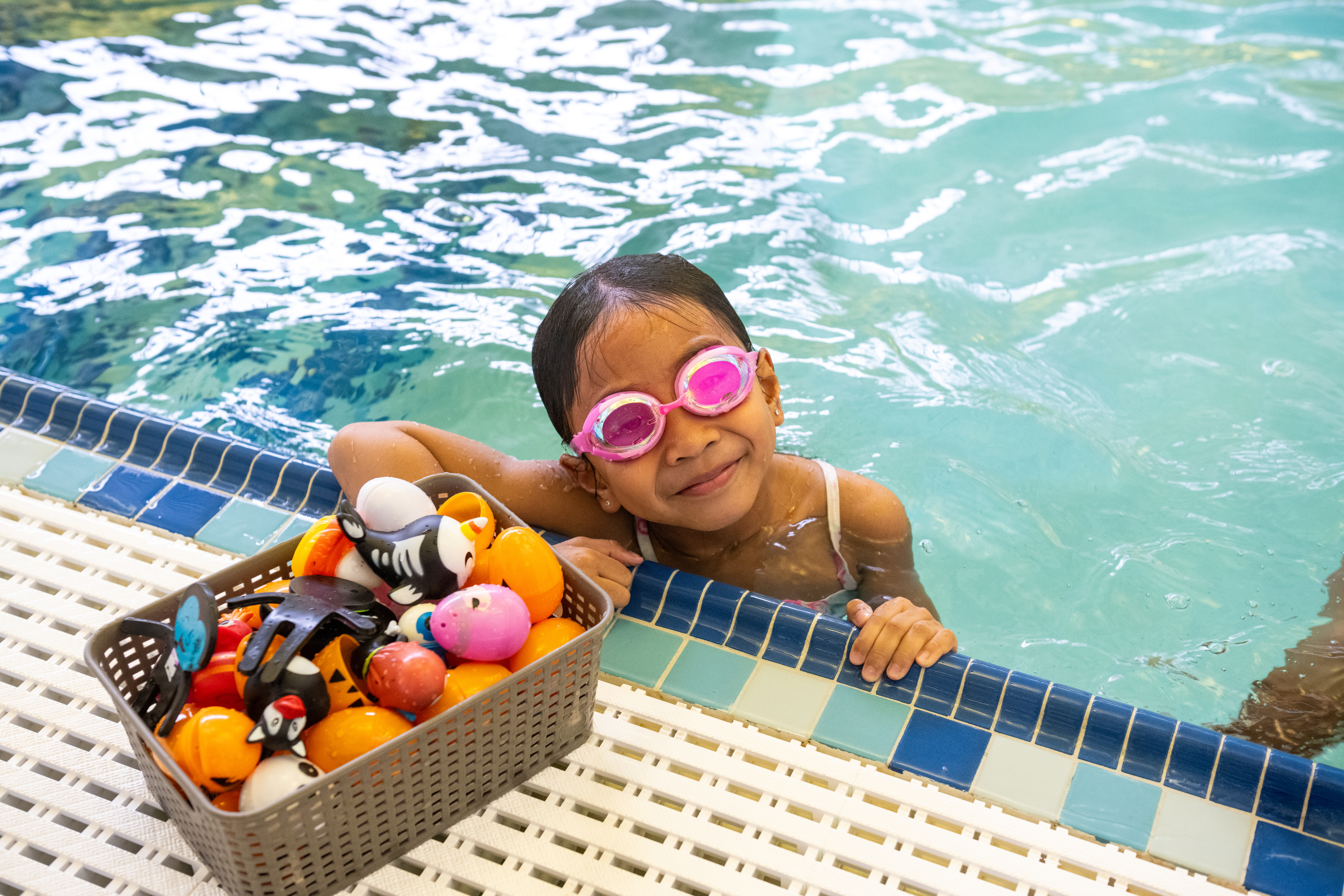 Girl in pool with toys in a box
