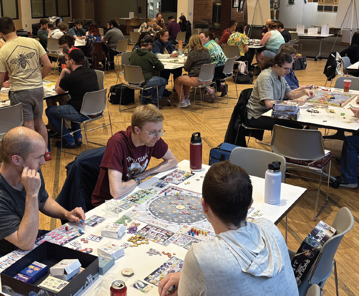 People playing board games at tables in a community center.