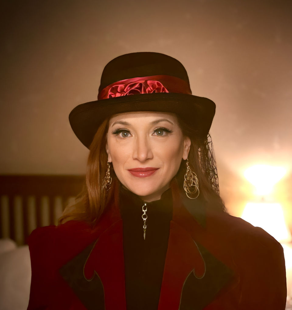 Portrait of a woman wearing a black hat with a red ribbon and a red jacket, looking at the camera.