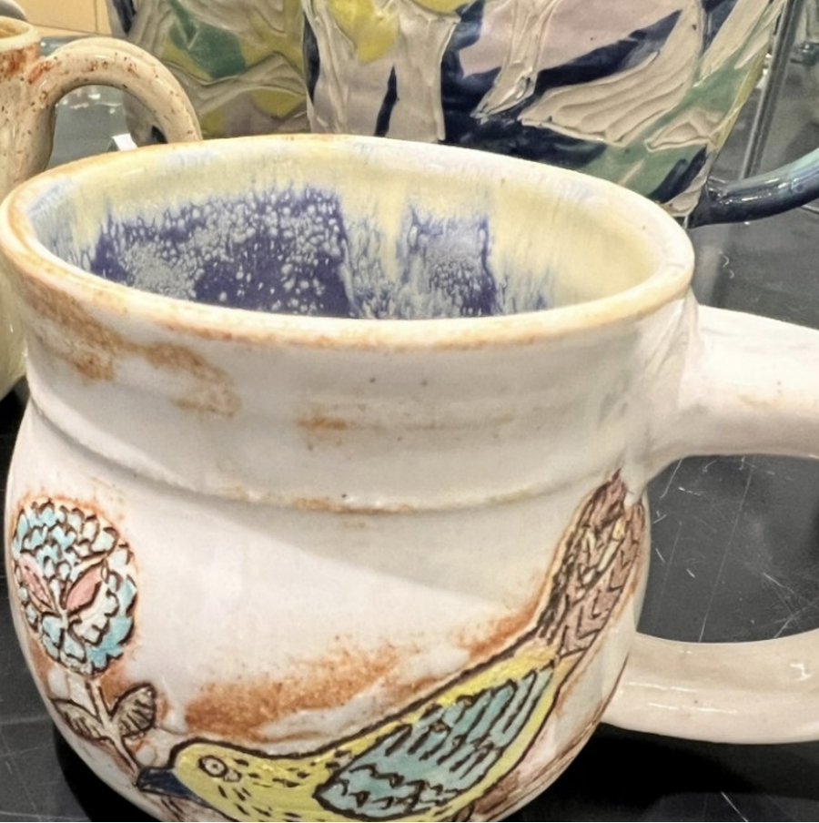 Handmade ceramic mug decorated with a bird and flower.