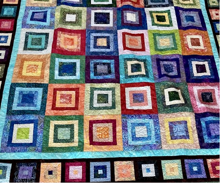 Colorful quilt with geometric square patterns.