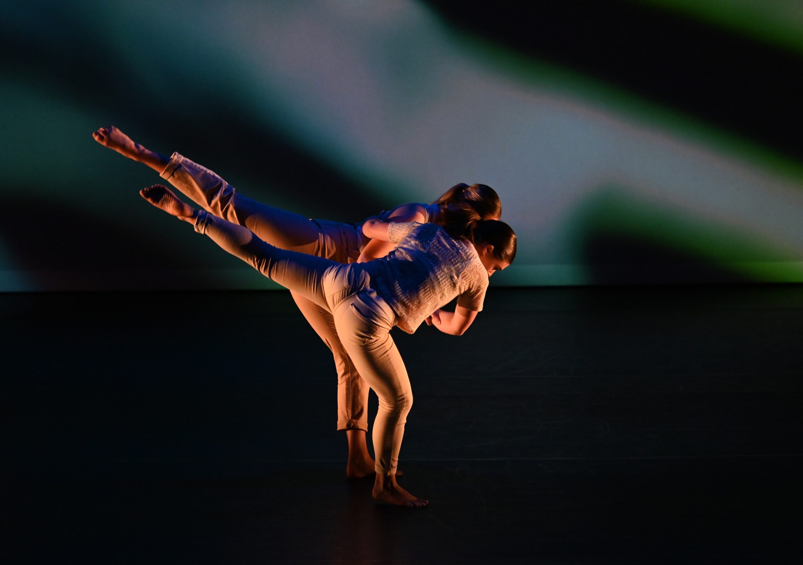 Two dancers performing a contemporary duet on stage under dramatic lighting.